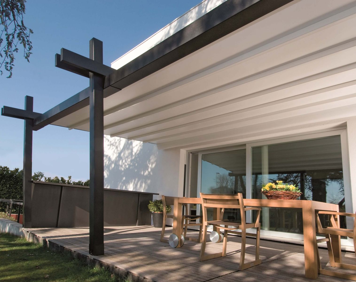 black wooden pergola with cream shade extended out over small patio area